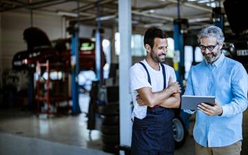 2 business internet customers looking at iPad inside a car repair shop